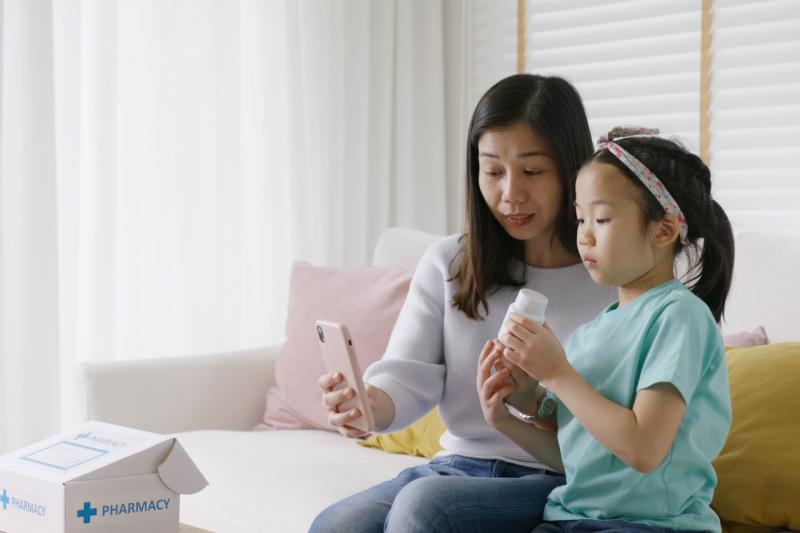 a mom and daughter looking at a phone while taking medicine